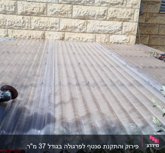 כלי עבודה על גג פלסטיק שקוף ליד קיר אבן